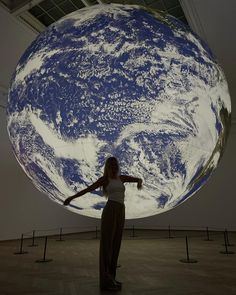 a woman standing in front of a giant blue and white earth image on the wall