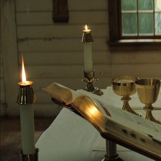 an open book sitting on top of a table next to candles