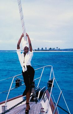 a woman standing on top of a boat holding onto the side of her head with both hands