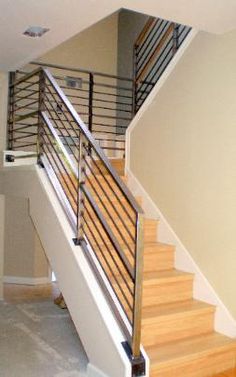 an empty room with stairs and railings in the center, next to a door