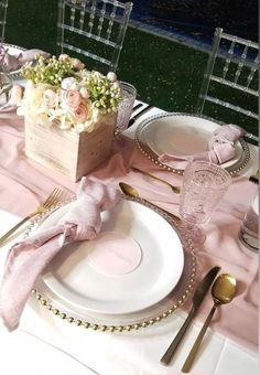 a table set with plates, silverware and pink napkins for a formal dinner