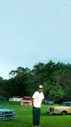 a man standing in the grass next to cars