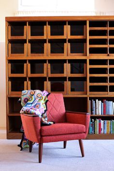 a red chair sitting in front of a book shelf