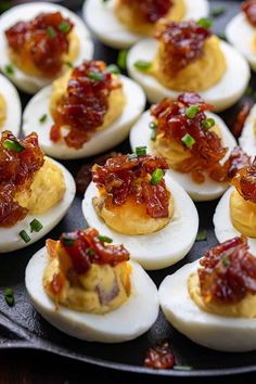 deviled eggs with bacon jam and green onions on them are arranged in a griddle