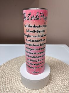 a pink and white cup sitting on top of a round table with a poem printed on it