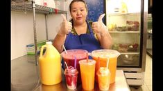 a woman is making drinks in front of her refrigerator with two thumbs up and three glasses on the counter