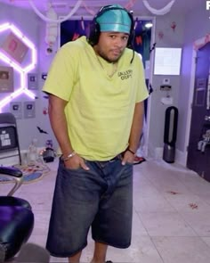 a man standing in a room with headphones on and wearing a yellow t - shirt