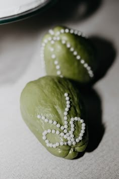 two green doughnuts with white frosting on them sitting next to each other