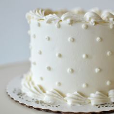 a close up of a white frosted cake on a plate with an ornate design