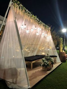 a tent set up on the grass with lights hanging from it's sides and plants in pots