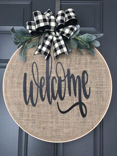 a welcome sign hanging on the front door with a black and white checkered bow