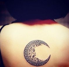 a woman's back with a crescent tattoo on it