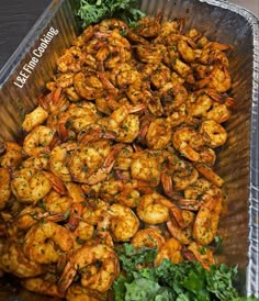 a tray filled with cooked shrimp and greens