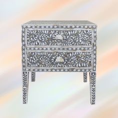 an ornate white and silver dresser with drawers on it's sides, against a multicolored background