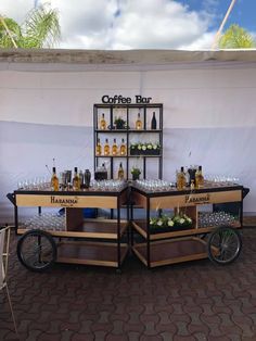 two tables with bottles and glasses on them in front of a white wall that says coffee bar