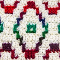 a crocheted blanket with green, red and white squares