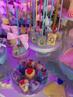 a table topped with lots of cakes and cupcakes covered in frosting next to candles