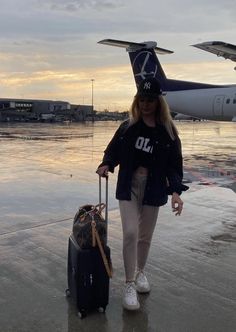 a woman is walking with her luggage on the tarmac