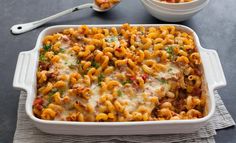 a casserole dish with pasta and meat in it next to a bowl of soup