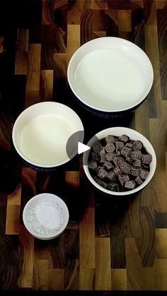 three bowls with chocolate chips in them on a wooden table next to milk and butter