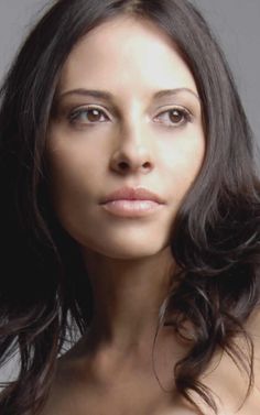 a woman with long dark hair is posing for the camera