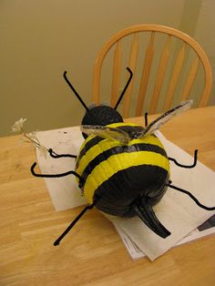 a yellow and black bee sitting on top of a piece of paper next to a wooden chair