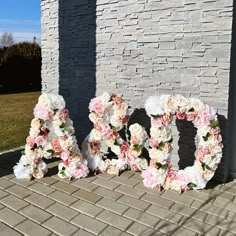 the word love spelled out with flowers in front of a brick wall