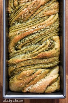 a loaf of bread with pesto on top in a baking pan, ready to be baked