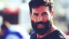 a man with a goatee and beard smiling at the camera while wearing a black t - shirt