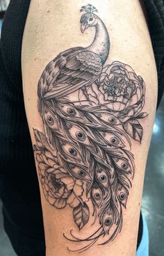 a woman's thigh with a peacock and flowers tattoo design on the side of her leg