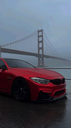 a red car parked in front of the golden gate bridge on a foggy day