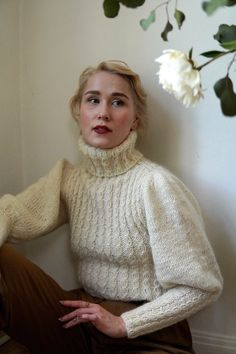 a woman sitting on the floor wearing a sweater