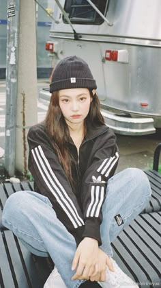 a young woman sitting on top of a metal bench