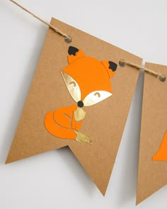 a brown paper banner with an orange fox cut out on it's side hanging from a string