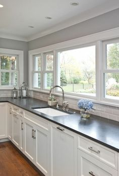 a large kitchen with white cabinets and black counter tops, along with an island in the middle