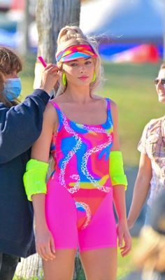 a woman in a neon colored swimsuit is getting her hair styled by a man