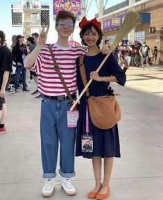 two people dressed up in costumes and holding brooms pose for the camera at an outdoor event