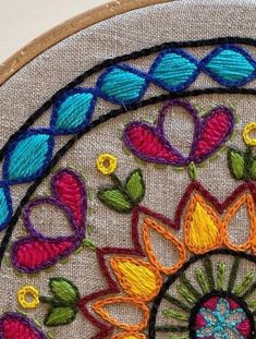 a close up of a colorful embroidery on a piece of cloth with flowers and leaves