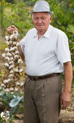 an older man holding up some onions in his hands