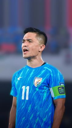 a soccer player with his mouth open and wearing a blue shirt that has white spots on it