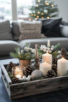 a tray with candles, pine cones and other decorations on top of a table in front of a christmas tree