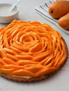 a pie with orange icing sitting on top of a table next to some fruit