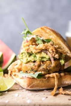 a close up of a sandwich on a table with watermelon and limes