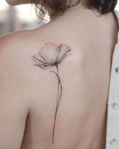 the back of a woman's shoulder with a single flower tattoo on her left shoulder