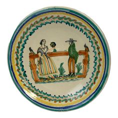 a decorative bowl with two people sitting on a bench, painted in green and yellow