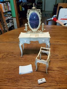 a doll house vanity with mirror and step stool on the floor, next to it's contents