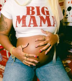 a pregnant woman with her hands on her belly wearing gold rings and matching ring bracelets