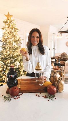 a woman standing in front of a christmas tree holding a piece of food and smiling