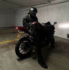 a man sitting on a motorcycle in an empty parking garage with no one around him