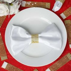 a white plate topped with a bow tie on top of a red and gold table cloth